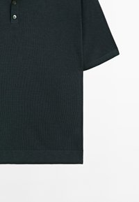 Mörkgrön polo skjorta, kort ärm, ribbad krage och fåll, två-knapps knäppning, gjord av mjukt bomullstyg, enkel design.