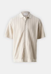 Kremowa koszulka polo z krótkim rękawem, wykonana z dzianiny o fakturze z wzorem jodełki, zapinana na pięć guzików, z prążkowanym kołnierzem.