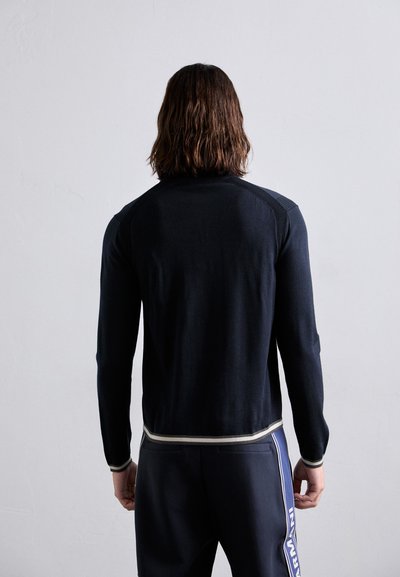 Bluza din tricot cu mânecă lungă, de culoare bleumarin, cu un design ajustat, având manșete ribbate în contrast și un stil elegant, minimalist.