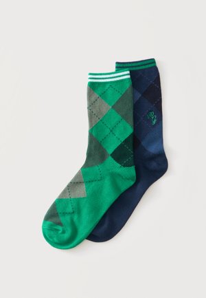 Dos calcetines con patrón de rombos argyle, uno verde con diamantes grises y verde oscuro, otro azul marino con diamantes azul más oscuro, ambos con puños a rayas.