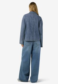 Jeansjacka i ljusblått med långa ärmar, krage och rak skärning. Kombinerad med vida jeansbyxor i matchande färg.