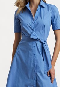 Blå skjortklänning i lätt bomull med korta ärmar, knäppning framtill, knytbart midjeband och en vida kjol, med en mjuk textur.