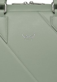 Grüne Kunstlederhandtasche mit diagonalen Nahtdetails, silbernen Beschlägen und eingeprägtem "VUCH"-Logo auf der Vorderseite. Glatte Textur.