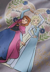 Tkanina z postaciami animowanymi Anny i Elsy w kolorowych sukienkach. Wzór zawiera kwiatowe akcenty oraz napis "Dwie Siostry, Jedno Serce."