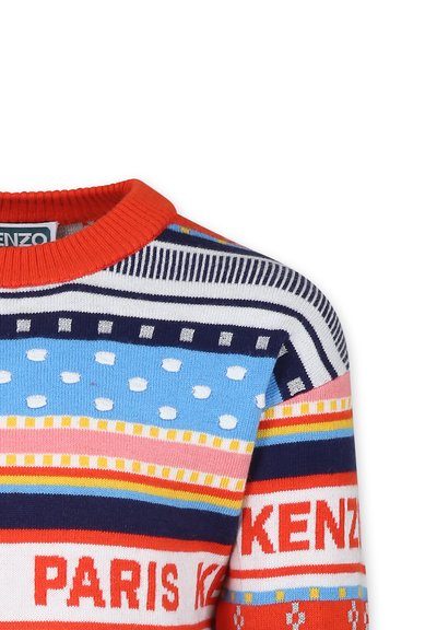 Pull multicolore avec un col rond orange, arborant un motif rayé en bleu, rouge, blanc et jaune avec des détails textuels.