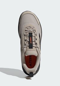 Szare siateczkowe sneakersy z czarnymi akcentami, z okrągłym noskiem, regulowanym sznurowaniem, wyściełanym kołnierzem i teksturowaną podeszwą. Wyświetlone logo "TERREX".