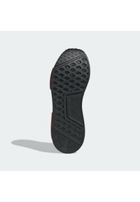 Černá gumová podrážka s hexagonálním vzorem, s červeným akcentem podél okraje a vzkleným logem uprostřed.