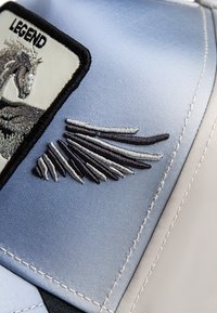 Blue satin cap featuring a white and gray embroidered patch with "LEGEND" text and a winged design. Textured stitching details are present.