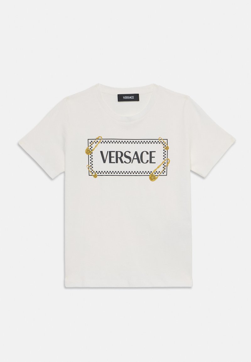 Vit bomull t-shirt med en svart och guld "VERSACE" logotyp med en rutigt mönster runt kanten och säkerhetsnålselement. Rund halsringning, korta ärmar.