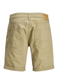 Pantalones cortos de algodón beige con dobladillos enrollados, que cuentan con dos bolsillos traseros con costuras curvadas y una etiqueta rectangular de cuero en la cintura.