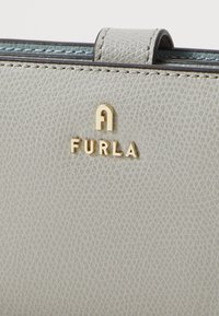 Lichtgrijze gestructureerde leren portemonnee met het gouden "Furla" logo, met een glad, gestructureerd ontwerp en een subtiel, geëmbossieerd patroon.