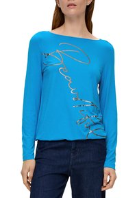 Niebieska koszula z długim rękawem, wykonana z miękkiego materiału, z kursywnym metalicznym złotym napisem "Piękna" ukośnie na przodzie.