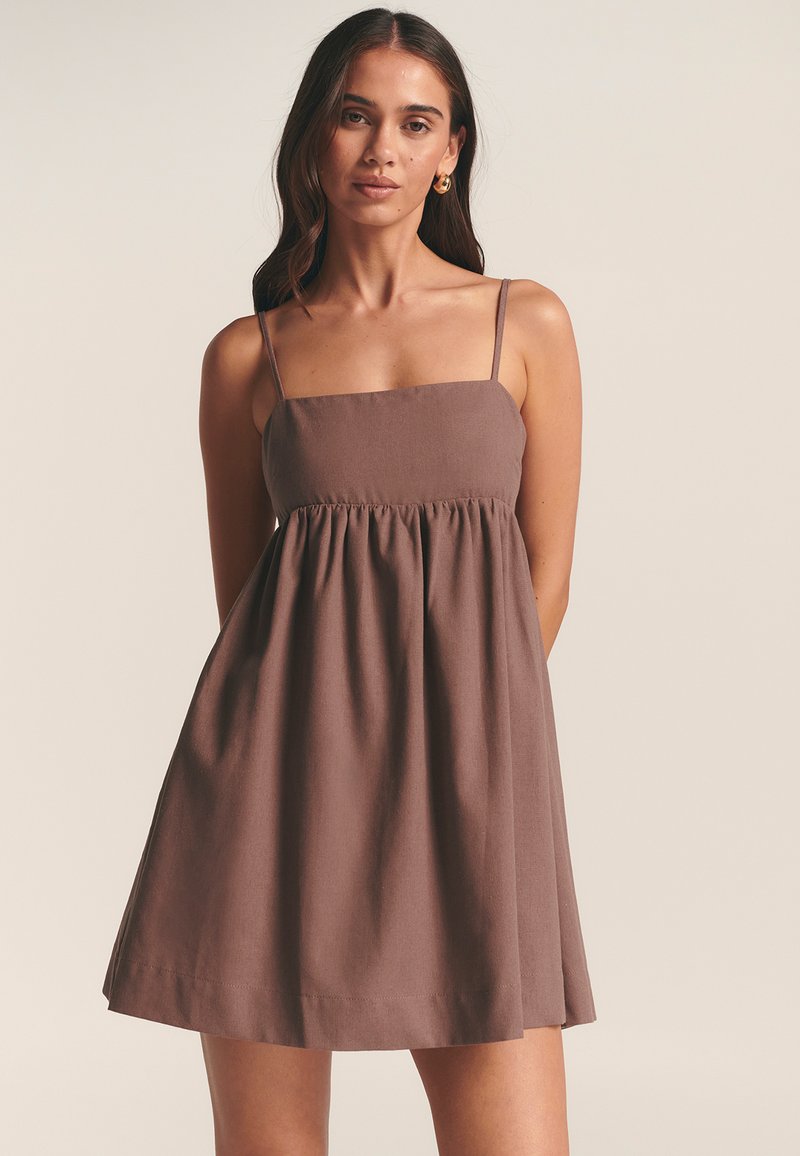 Abito marrone senza maniche con scollo quadrato, vita arricciata e gonna svasata. Realizzato in un tessuto morbido e leggero. Design semplice.