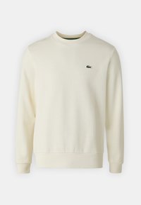 Off-white långärmad sweatshirt med ribbade muddar och nederkant, rund hals och liten grön krokodillogo på vänster bröst.