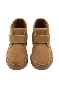 Botines de ante color marrón claro con una correa de velcro, puntera redonda y suela de goma, que cuentan con costuras tonales y una textura suave.