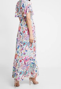 Maxi-kjole med et blomsterprint i livlige farver på en lys baggrund. Stoffet er let, med korte flæseærmer og en flæset kant.