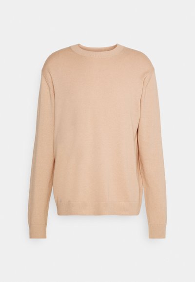Sweater bege claro em um ponto macio e texturizado. Apresenta um decote redondo e punhos e bainha canelados, evidenciando um corte descontraído e um tecido suave.