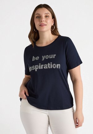 T-paita tummansinisestä kankaasta, pyöreällä kaula-aukolla, lyhyillä hihoilla ja metallisilla "ole oma inspiraatiosi" -teksteillä. Pehmeä puuvillasekoite.