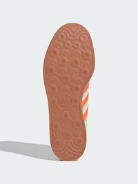 Podeszwa sneakerów Adidas z teksturowaną gumową powierzchnią w odcieniach pomarańczowym i beżowym. Wyraźne okrągłe wzory chwytne oraz logo umieszczone w centrum.
