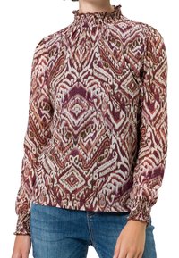Blouse à manches longues avec un col à volants. Présente un imprimé abstrait coloré dans des nuances de bordeaux, crème et vert. Manches à smocks.