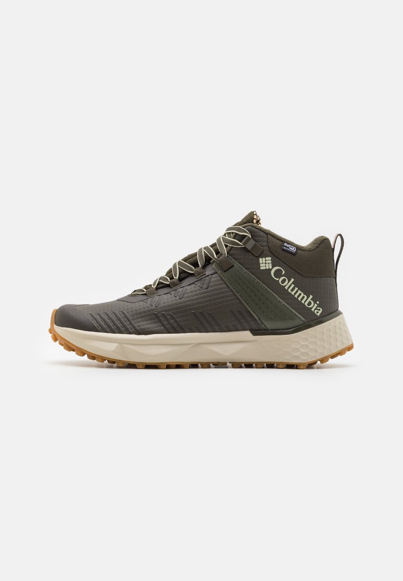 Chaussure de randonnée montante vert foncé avec semelle beige, semelle extérieure texturée, lacets, languette et logo Columbia sur le côté.
