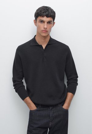 Polo a maniche lunghe nera con colletto, dotata di tre bottoni sulla patta e una vestibilità morbida. Indossato con pantaloni in denim scuro.