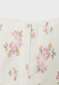 Tissu blanc avec imprimés floraux roses et pêche, avec une fermeture éclair dissimulée centrée.