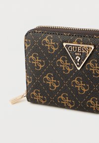 Čierna syntetická peňaženka so zlatým vzorom a logom. Obsahuje zlatý zips a detail prešívania. Kompaktný obdĺžnikový tvar.