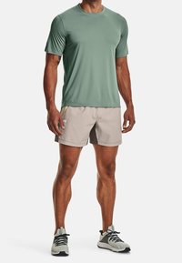 Jasnozielona, krótko rękawowa koszulka sportowa w połączeniu z beżowymi szortami, z żółtymi akcentami. Założone z szarymi butami sportowymi.