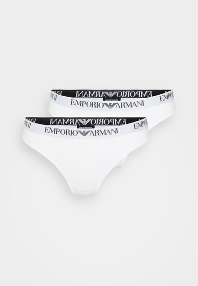 Thong en coton blanc avec une ceinture élastique noire portant le logo "Emporio Armani" en blanc. Texture lisse et design minimaliste.