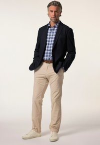 Herroutfit med en mörk kavaj, blå och vit rutmönstrad skjorta, beige byxor och vita sneakers. Enkel design med rena linjer.