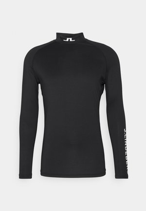 Black long-sleeve shirt with high collar, made from stretchy fabric. Features white logo text along the right sleeve. Smooth texture.