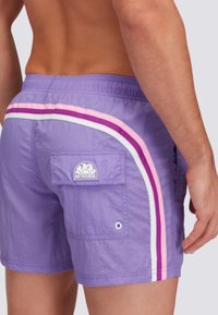 Pantaloni da nuoto viola con un tessuto testurizzato, dotati di strisce bianche, rosa e viola scuro e una tasca posteriore con un'etichetta logo.