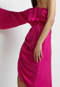 Fuchsiové saténové šaty s designem na jedno rameno, širokými rukávy a nabíraným detailem v pase, s jemným texturovaným vzorem.