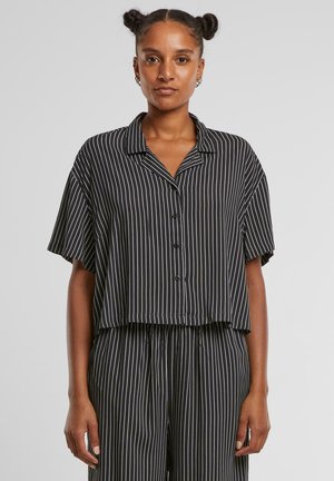 Camisa de manga corta a rayas verticales en blanco y negro con cuello, presenta un corte cuadrado y cierre de botones.