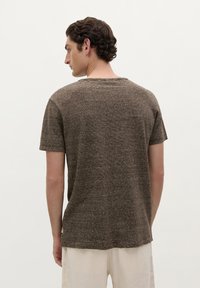 Camiseta de manga corta a rayas marrones con un cuello redondo y un ajuste relajado. Textura suave, con rayas horizontales en diferentes tonos.