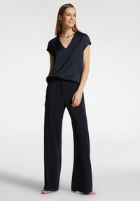 Top blu navy a maniche corte con scollo a V abbinato a pantaloni larghi. Tessuto liscio con vestibilità ampia, design minimalista, senza motivi visibili.