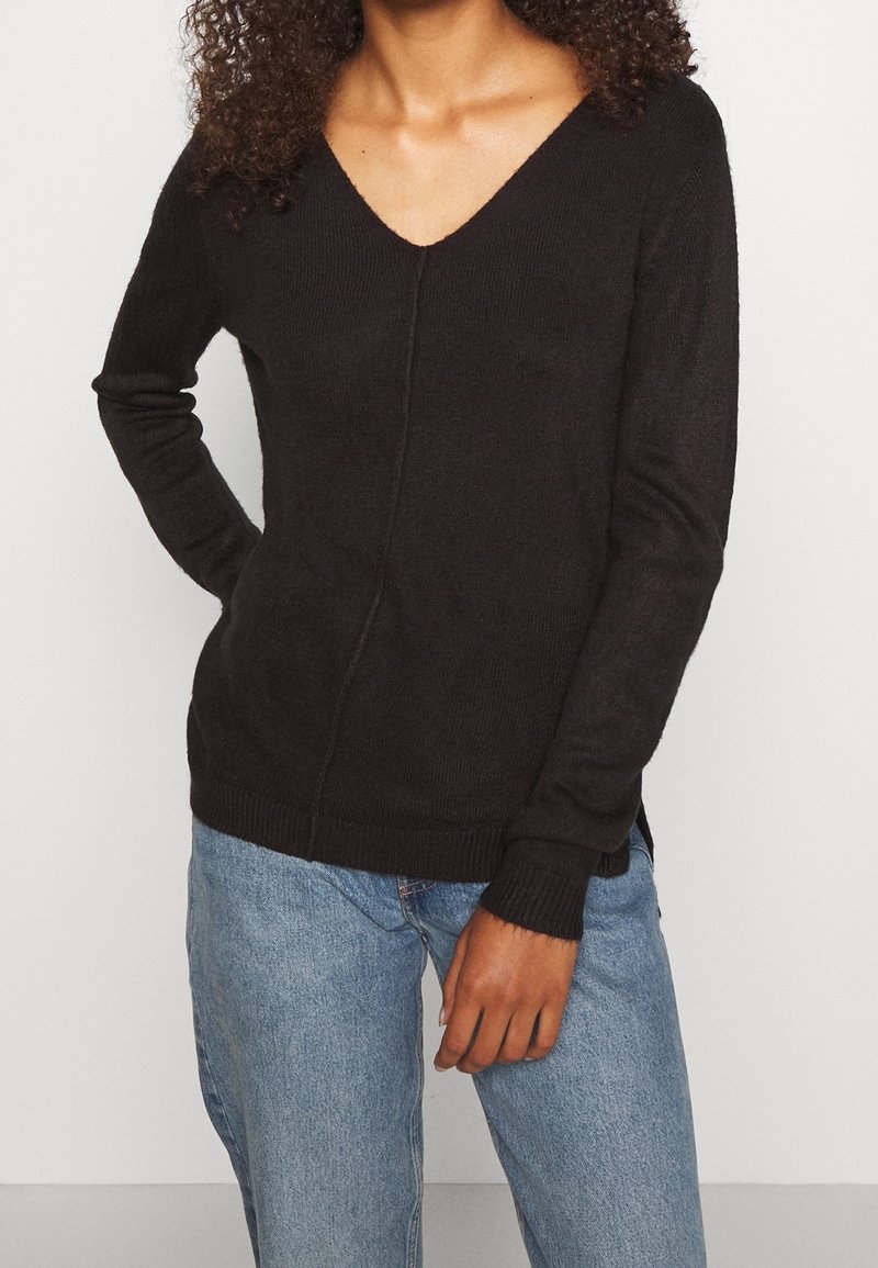Maglione nero a scollo a V con maniche lunghe, realizzato in morbido tessuto lavorato a maglia. Presenta una cucitura sottile sul davanti e polsini e orlo a coste.