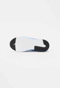 Semelle de chaussure de sport avec une section en caoutchouc noir texturé, une semelle intermédiaire blanche et des accents bleus ; comporte des rainures pour l'adhérence et la flexibilité.
