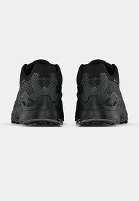 Zapatillas deportivas negras con tejido texturizado, refuerzo en el talón y suela de goma con relieve. Presentan un patrón geométrico en el lado del talón.