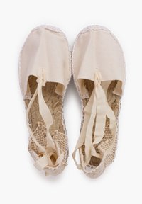 Scarpe in tessuto beige con suola in juta intrecciata, dotate di una parte superiore morbida in cotone e lacci per una vestibilità sicura. Il bordo è rifinito in bianco.