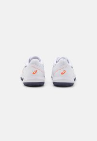 Zapatillas deportivas blancas con un upper texturizado, que presentan acentos en naranja, una suela acolchada y un agarre con patrón en la suela exterior.