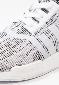 Adidas-sneaker som har en textilovandel i svart och vitt mönster, grå accenter, vita snören och en texturerad vit mellansula med logotyp.