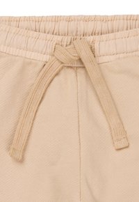 Beige sweatpants met een elastische tailleband en een trekkoord. De stof heeft een zachte textuur en de naden zijn netjes afgewerkt.