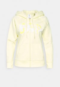 Haut à capuche zippé jaune avec cordon de serrage, portant le logo "GAP" en blanc et jaune clair. Fabriqué en tissu doux avec deux poches avant.