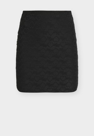 Mini-jupe noire avec des motifs de cœurs en relief et un motif de texte en écriture cursive sur tout le tissu.