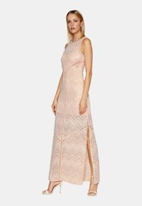 Abito lungo in cotone color pesca chiaro con motivo a zig zag, fessure laterali, design senza maniche e silhouette aderente. Sandali piatti completano il look.