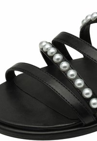 Sandal negra con tres correas delgadas con acentos de perlas, hecha de material sintético suave con una suela texturizada.