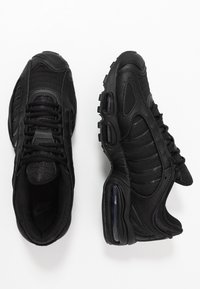 Černé tenisky Nike s mesh a syntetickým materiálem, zaoblenou špičkou, texturovanými boky a vzduchovou vložkou v patě pro odpružení.