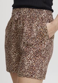 Braune Shorts mit Leopardenmuster, elastischem Bund und Seitentaschen. Aus leichtem Stoff, mit weicher Textur und lockerem Schnitt.